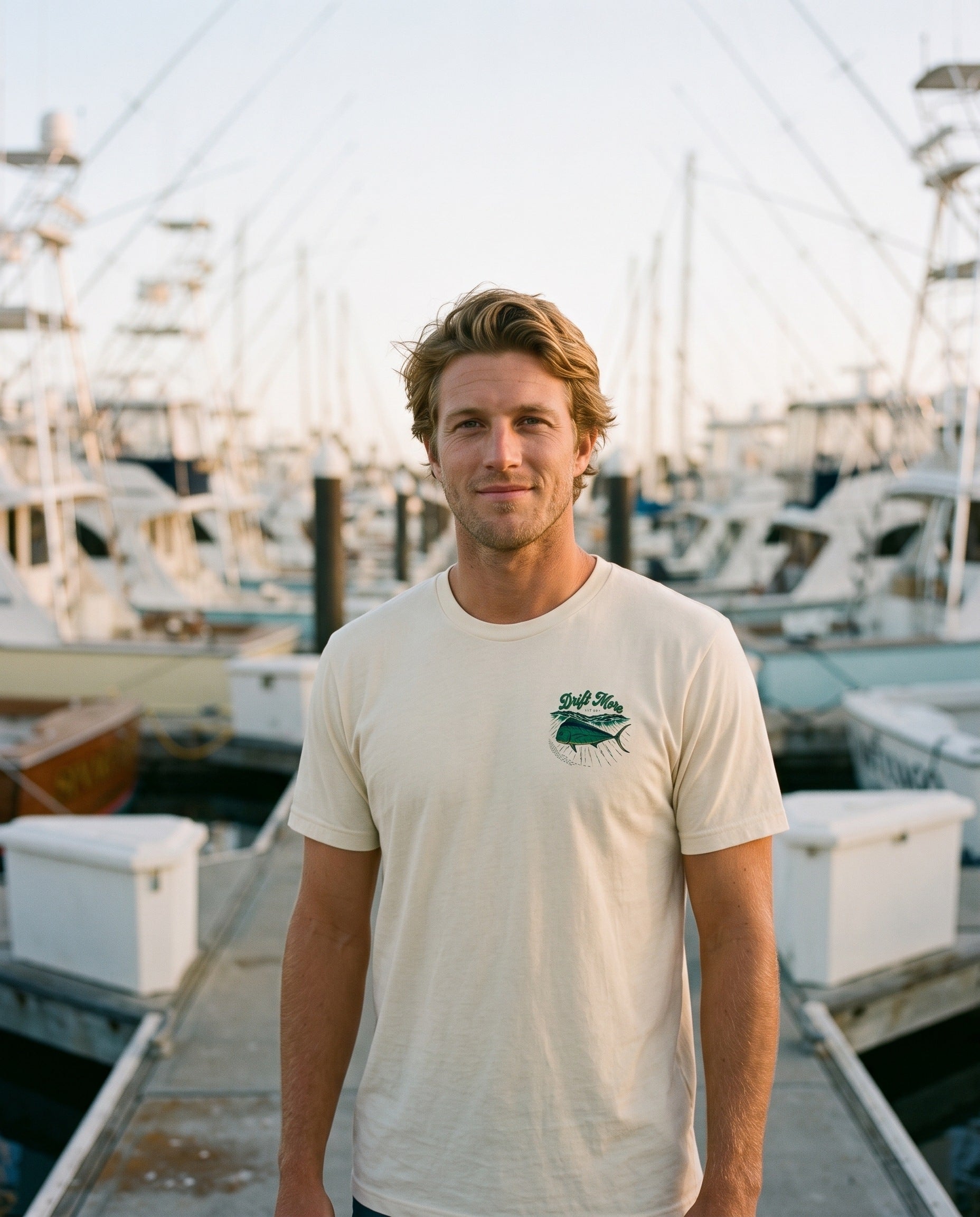 Mahi Lit Up Tee in natural cream, left-chest print, marina dock at golden hour