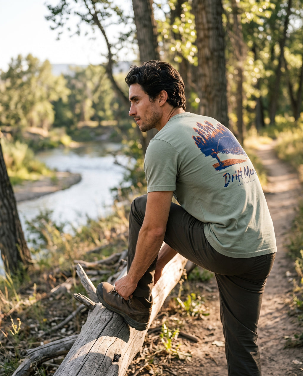 One More Cast Tee back print, sage green, on a river trail at late afternoon
