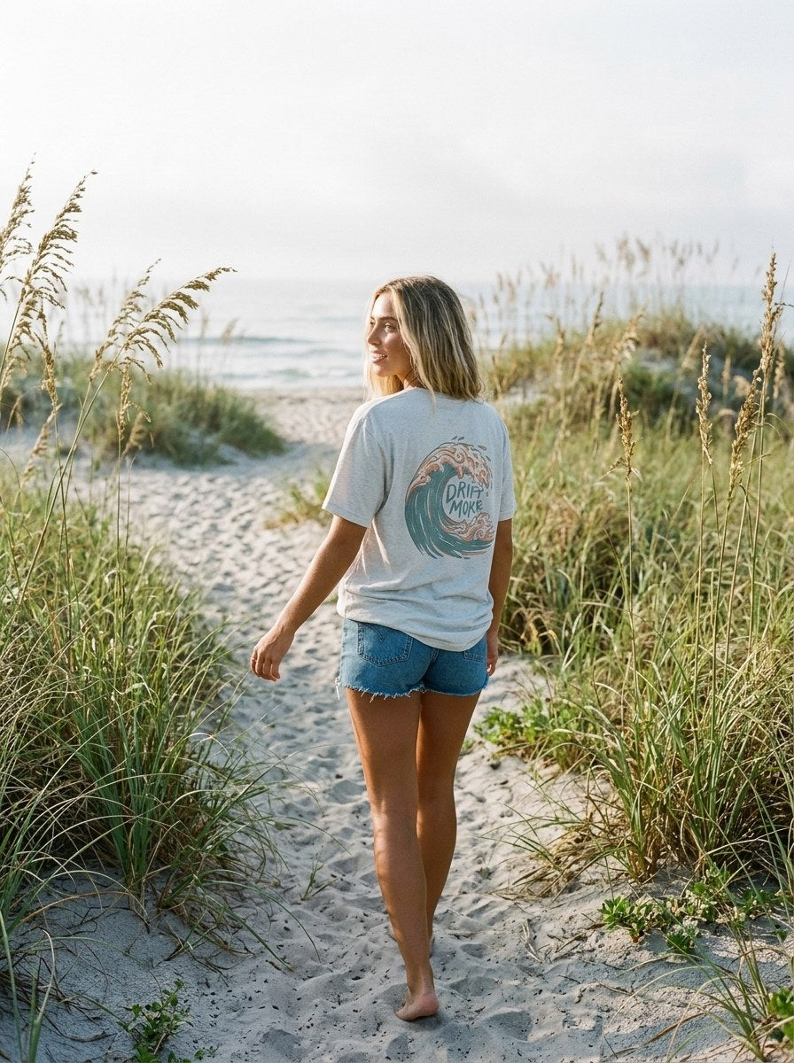 Drift More Curl Tee in Natural worn on a beach path, back print in view